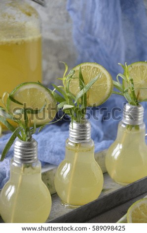 Fresh lime and lemon lemonade with estragon in a glass on a light grey desk