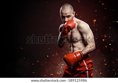 
Conceptual Portrait of brutal boxer in fire sparks and smoke. 
red boxing gloves. Art Sport background. Royalty-Free Stock Photo #589125986