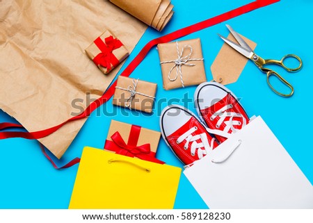 cool shopping bags, red gumshoes and beautiful gift near things for wrapping on the wonderful blue background