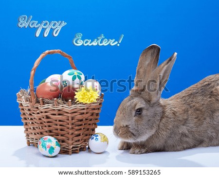 Brown rabbit lying near Easter basket with colored  and painted eggs