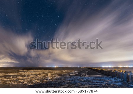 Long stone and metal pier in the sea bay in the starry night