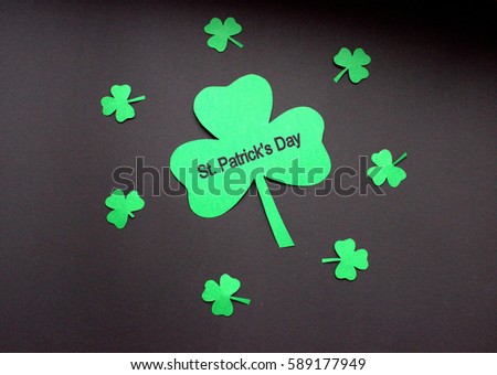Text St. PAtrick's Day on clover or shamrock with black background in round of little shamrocks