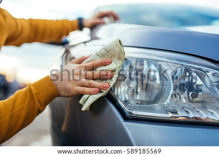 Shot of man polishing his car with a cloth. Royalty-Free Stock Photo #589185569