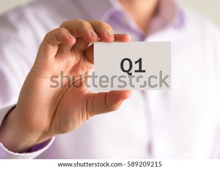 Closeup on businessman holding a card with Q1 QUARTER 1 message, business concept image with soft focus background and vintage tone