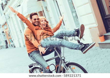 Young couple having fun in the city.Happy young couple going for a bike ride on a autumn day in the city.