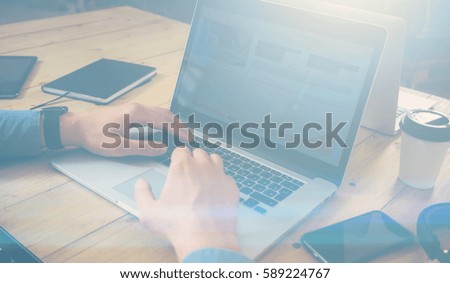 Businessman working at the wooden table with laptop.Male texting on notebook keyboard.Horizontal, visual effects