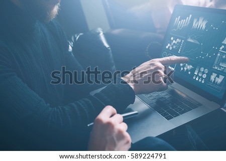 Young coworkers discussing business ideas at modern office.Bearded man poiting hand to laptop display.Woman sitting close him and holding pen on her hand. Horizontal, blurred, visual effect