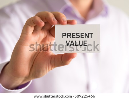 Closeup on businessman holding a card with PRESENT VALUE message, business concept image with soft focus background and vintage tone