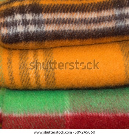 Stack of the beautiful colored woolen blankets in a yellow, brown, green color.  Close up. Everything for your warmness. Beautiful photo of a pile of nice light blankets. 