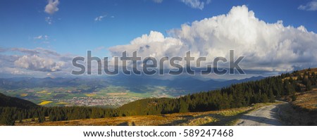 Panorama of sunny evening in mountains. White clouds above green valley. Summer evening on mountain top. Sunny summer background. Beautiful travel concept.