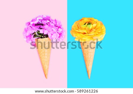 Two ice cream cone with flowers over colorful pink blue background top view