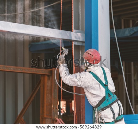 Worker paints a metal frame at construction site