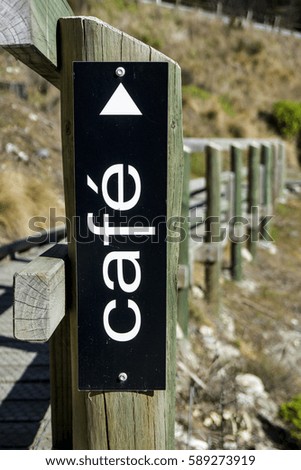 Actual signboard of cafe' and arrow on a wooden path