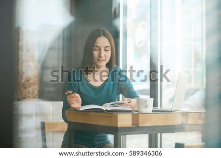 Young woman making notes while working at the cafe