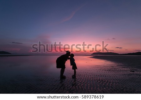 mom and daughter kissing on the beach