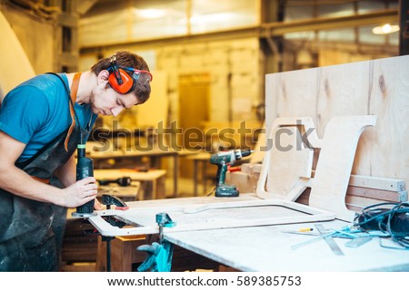 Professional cabinetmaker grinding wooden workpiece Royalty-Free Stock Photo #589385753