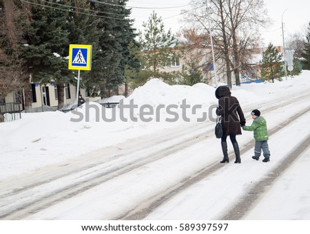 a woman leading a small child across the road at the place where the sign of a pedestrian crossing, the concept of traffic enforcement.