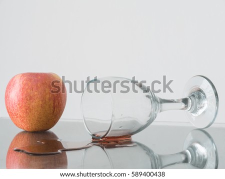 Wine glass falling with apple behind on white background,