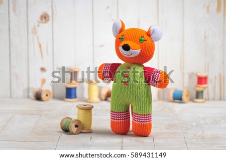 Knitted fox pup isolated on wooden background.