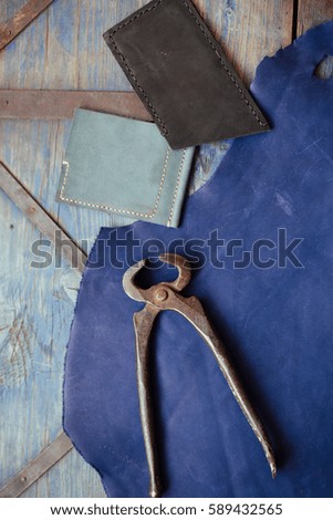 Leather craft and leather working. Piece of hide and working tools on a work textured blue table.