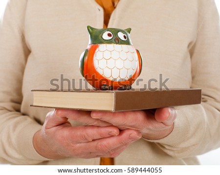 Close up picture of an elderly woman holding a book and an owl as the symbol of wisdom