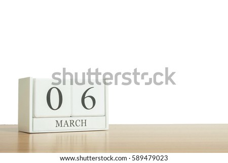 Closeup surface white wooden calendar with black 6 march word on blurred brown wood desk isolated on white background with copy space , selective focus at the calendar
