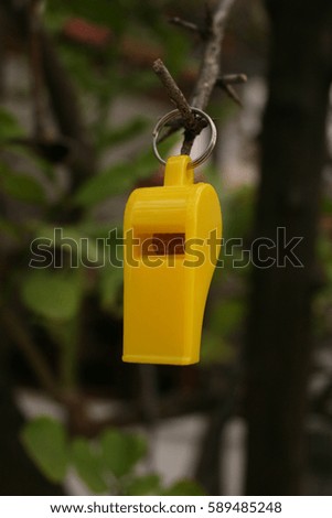 yellow whistle hanging on tree in natural background