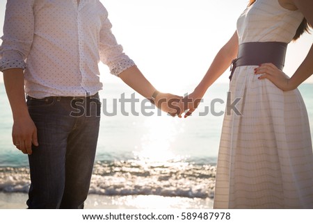 Man and woman holding hands on ocean sunset. Love, marriage and happiness.