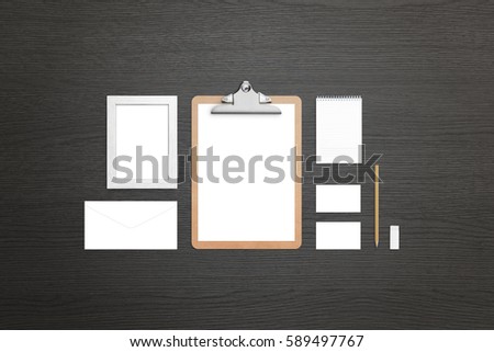 Clean stationery on black wooden table. Top view of isolated items for visual identity presentation. Clipboard, paper, pad, envelope, frame, business card presentation.