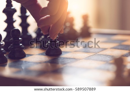 Detail of a woman's hand making the first move in a chess game, moving the pawn one field forward. Selective focus Royalty-Free Stock Photo #589507889