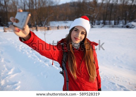 Pretty young female tourist takes selfie in winter. Portrait of young woman taking selfie outdoors