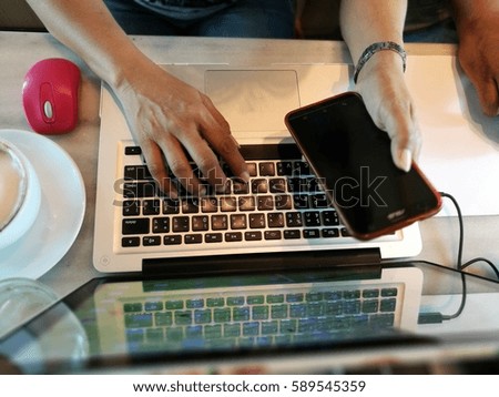 Hands of woman using computer keyboard and mobile
