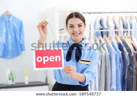 Female worker holding board in dry-cleaning salon