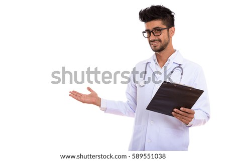Young happy Persian man doctor smiling while holding clipboard and showing something
