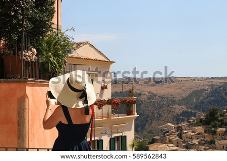 Italy, Sicily: Woman with hat is photographing Ragusa Ibla.