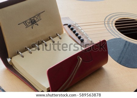 Leather notebook with black pen picture of an airplane on the background of a guitar