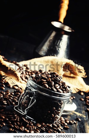 Coffee beans in a glass jar, black background, selective focus