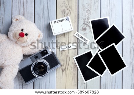 Retro camera with empty old instant paper photo album and teddy bear on wood background, top view (vintage style)