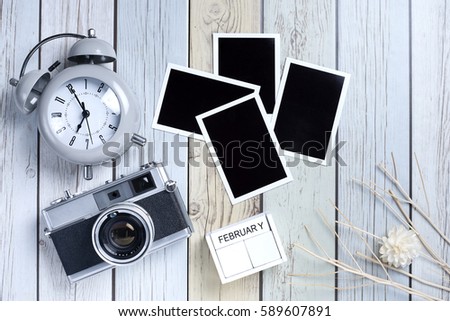 Retro camera and empty old instant paper photo album on wood background, top view (vintage style)
