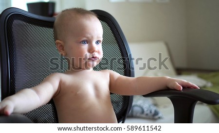 little boy sitting on a chair watching a cartoon