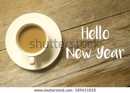 A cup of coffee with HELLO NEW YEAR written on a wooden table.