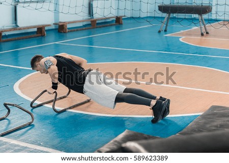 Young sportsman doing gymnastic exercise on hands in sports hall
