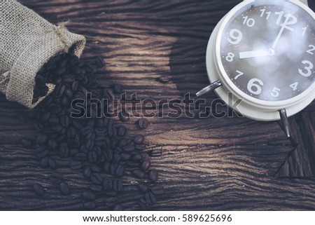 In selective focus of Vintage brouwn clock face and and coffee bean in sack fall on wooden table outdoor background.Coffee break for relax time concept- Vintage effect style pictures