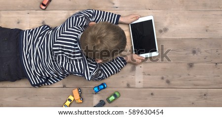 Modern generation. Kid playing on ipad Royalty-Free Stock Photo #589630454