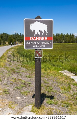 danger do not appoach wildlife,bison sign pole near by walkway.