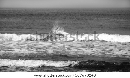 Young girl on the surfboard seen through the wave splash. Tel Aviv (Israel). Freedom concept. Black and white.