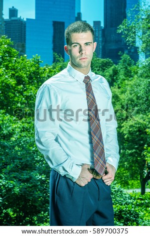 Portrait of Businessman in New York. Handsome professional guy wearing long sleeve white shirt, patterned tie, hands on belt, stands in font of business district, ready to work. Color filtered effect
