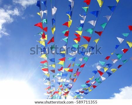 Multicolored flags on background sky. The sun in left bottom corner on image. 
