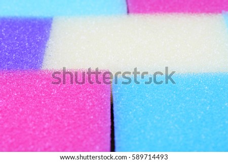 Cleaning kitchen sponge texture as background. Colorful yellow pink green purple blue multicolor sponges. Close up macro about sponges. Sponge pattern textures concept background or wallpaper 

