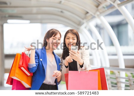 Happy shopping asia woman use smartphone with friends at the background.
